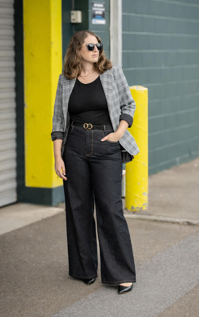 Woman wearing a gray check blazer, black top, and wide-leg jeans