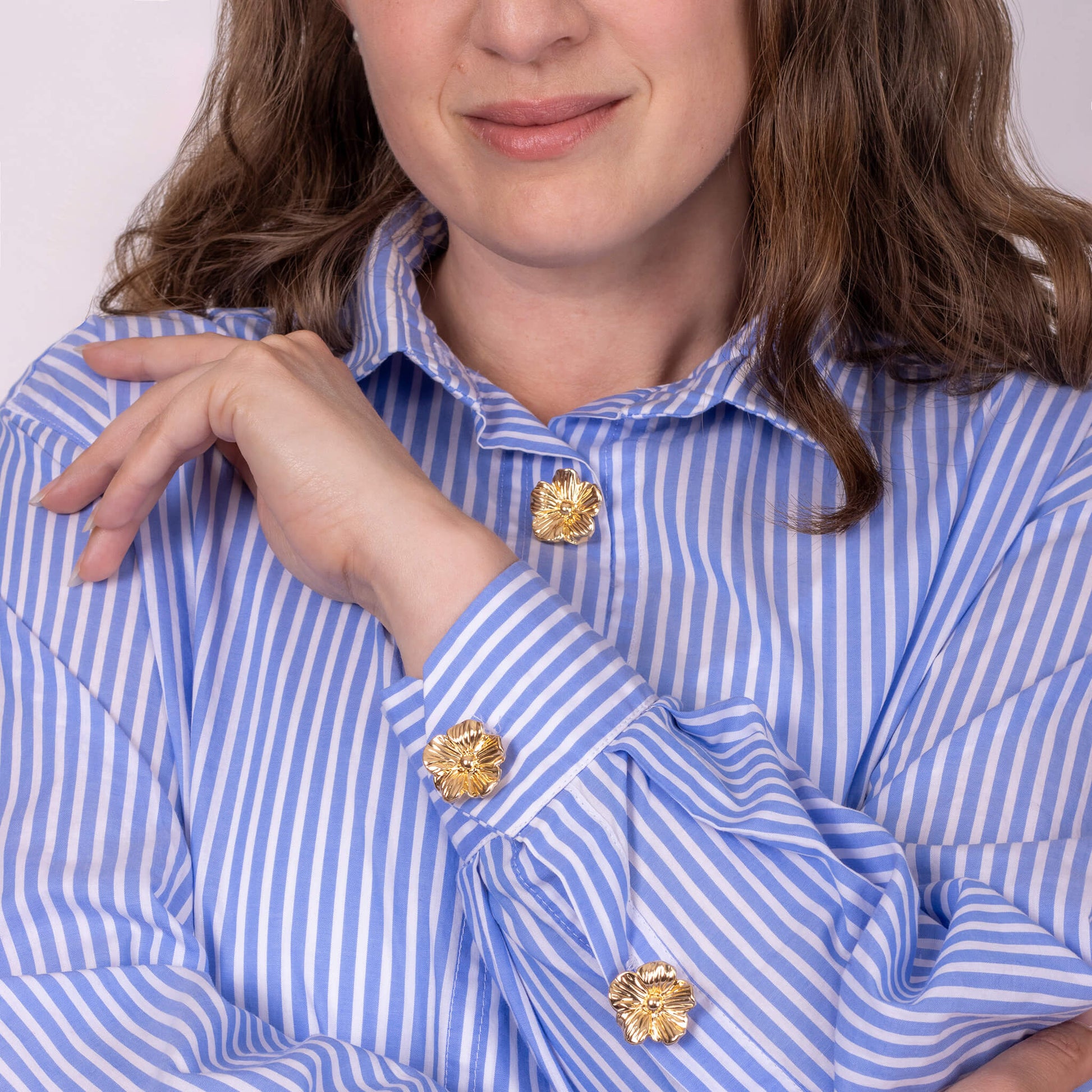 woman wearing a striped shirt with gold flower button covers