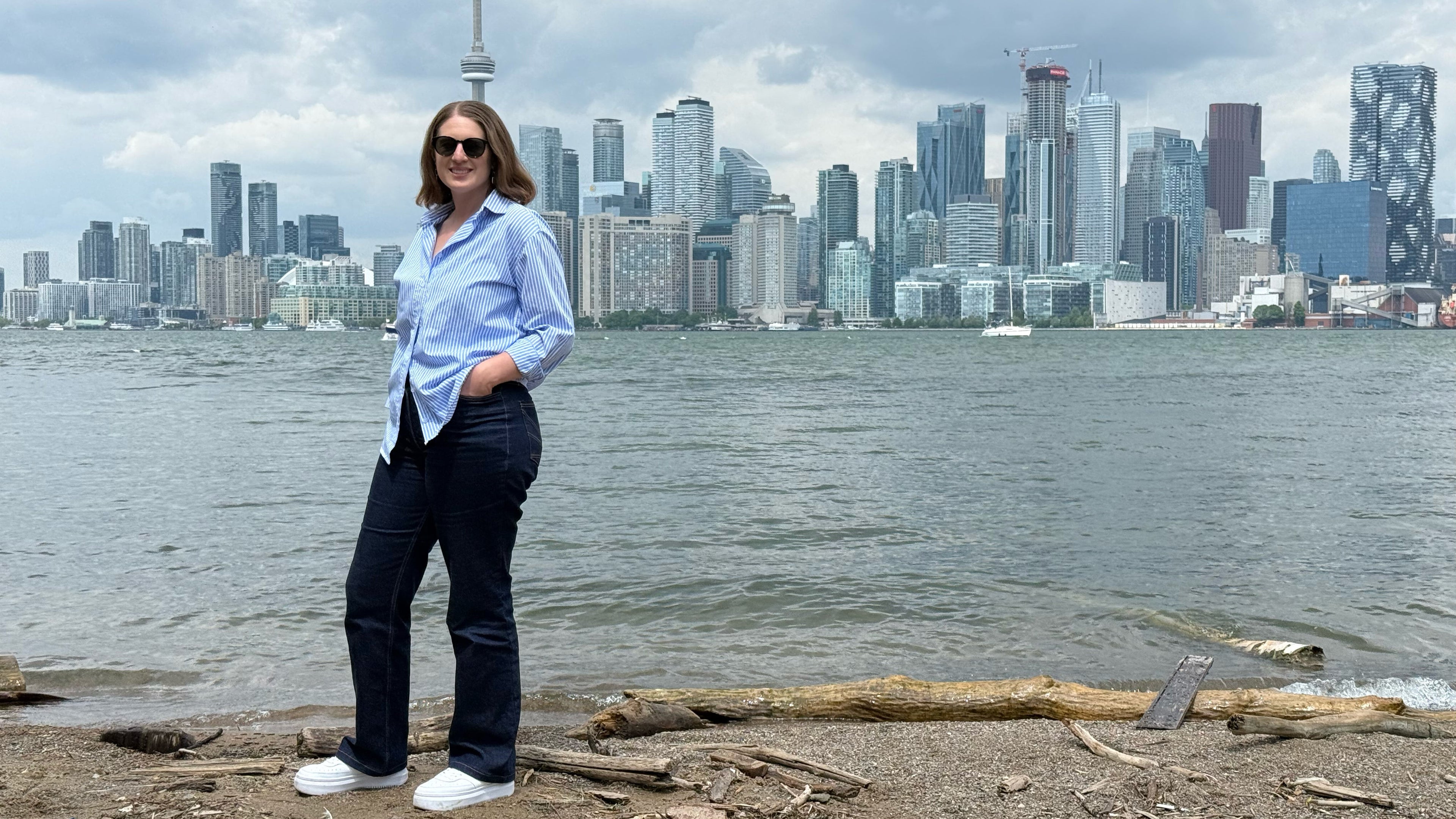 Desiree wearing jeans and striped shirt with toronto in the background